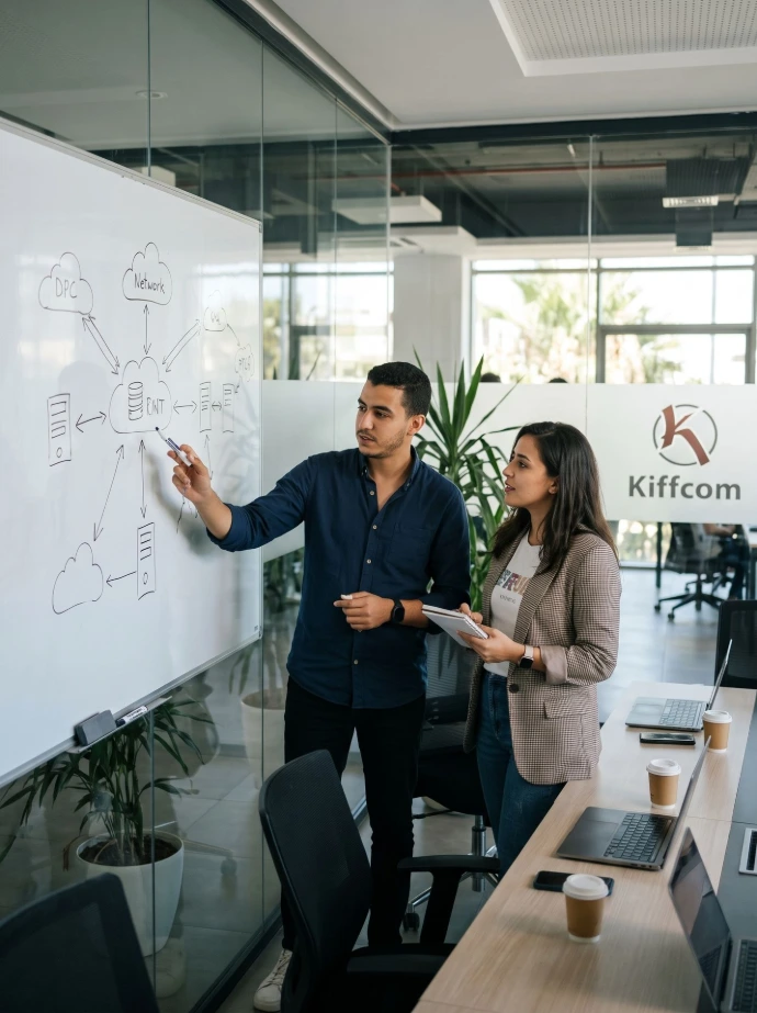 Tech professionals (a man and a woman) standing in front of a glass whiteboard in a stylish meeting room in Tunis